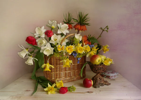 Bouquet of spring flowers . Still life with daffodils , tulips , Royal grouse , apples in a vase .