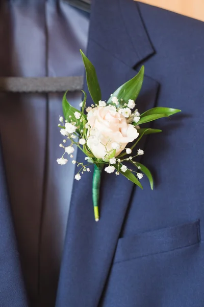 White rose boutonniere pinned to a grooms jacket.
