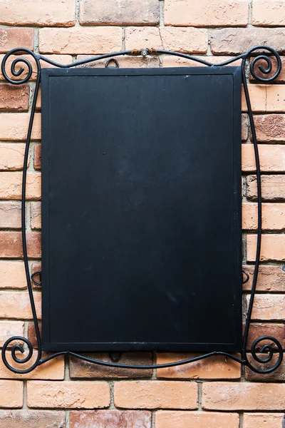 Blank blackboard at a brick wall