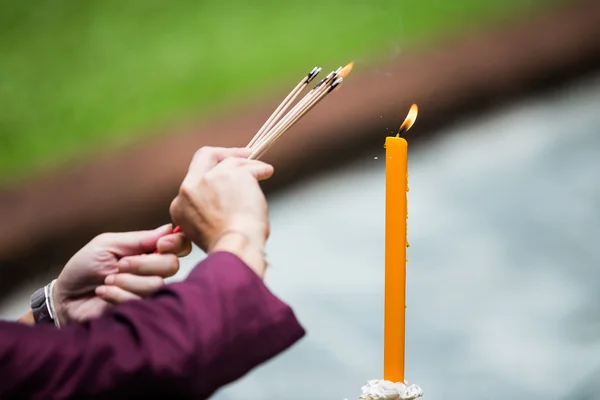 Man and woman hand lighting candles in a church