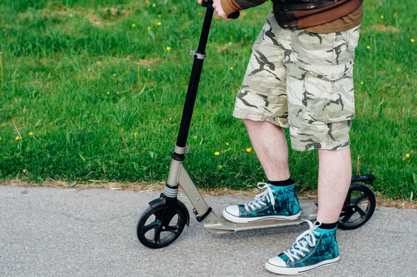 Legs of young man on kick scooter