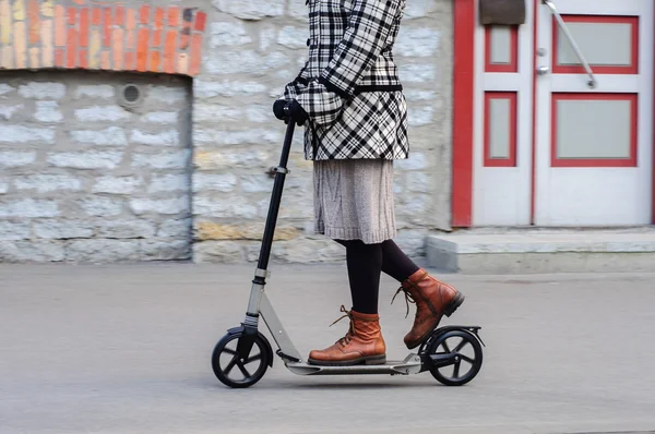 Girl in casual wear on kick scooter on street