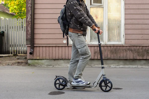 Young man in casual wear on kick scooter on street