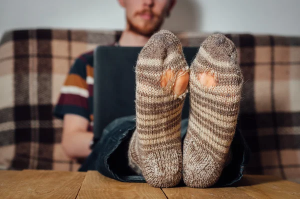 Young man working with laptop in holey socks