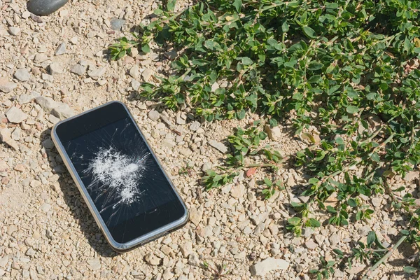 Broken mobile phone on sand concept