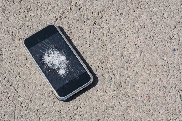 Broken mobile phone on asphalt concept