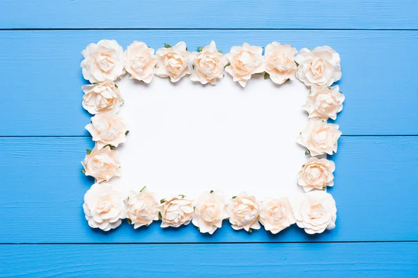 White paper sheet with frame made of roses on table
