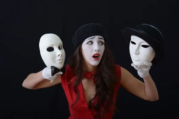 The girl is MIME holding a theatrical mask.on a dark background