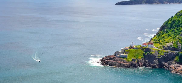 Rugged coastline and Atlantic ocean. Warm summer day in August.  Views from atop historically famous Signal Hill in St. John\'s. A speeding boat passing through appears slow relative to the vastness.