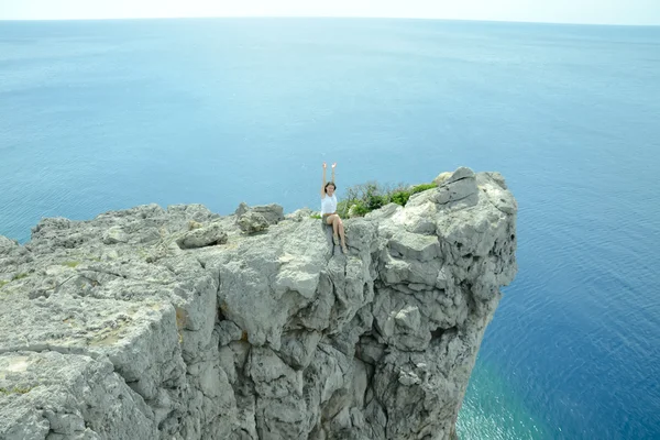 Girl sitting on cliff by the sea