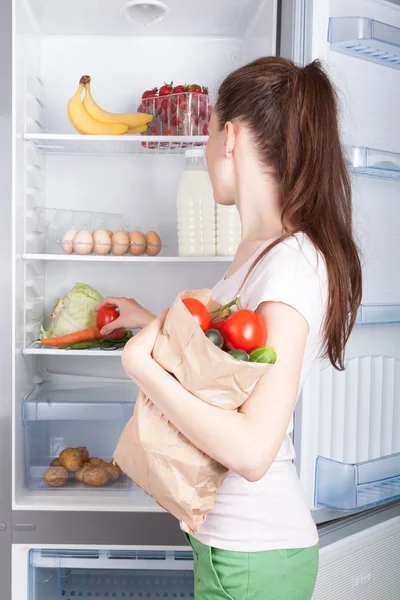 Woman near the refrigerator with healthy food.