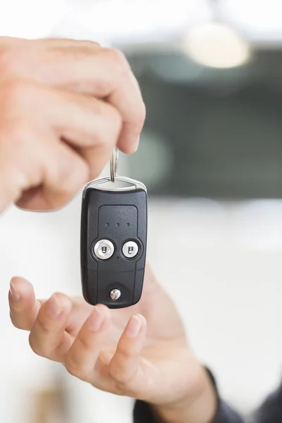 Salesman in car dealership giving keys to clients