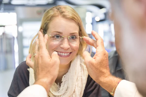 Woman in optical center trying eyeglasses on