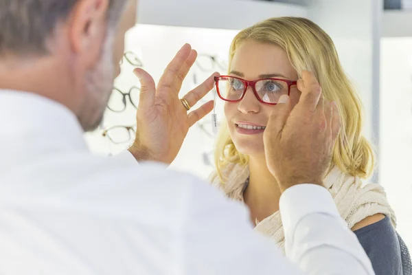 Woman in optical center trying eyeglasses on