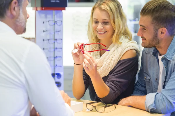 Woman in optical center trying eyeglasses on