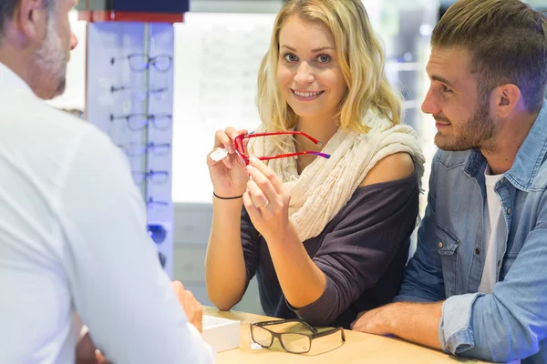 Woman in optical center trying eyeglasses on