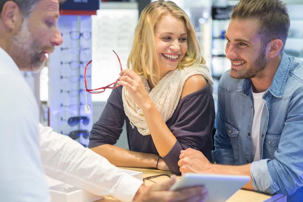 Woman in optical center trying eyeglasses on