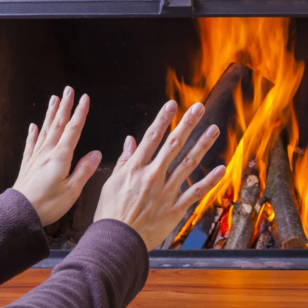 Woman warming hands at fireplace