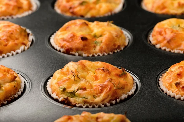Homemade muffins with chicken and cheese in black form for baking.
