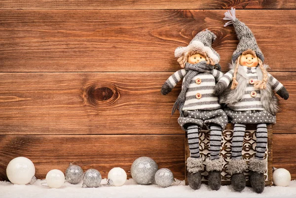 Christmas decorative elves sitting on the box. Picture made on the wooden background.