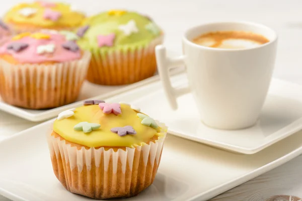 Muffins covered with icing sugar on white plate and cup of coffee.