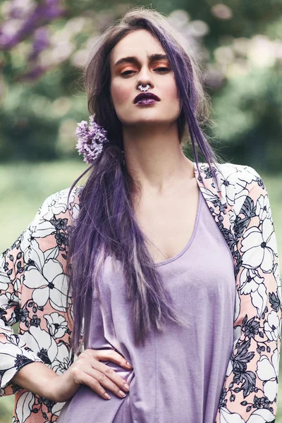 Woman with purple hair posing in park