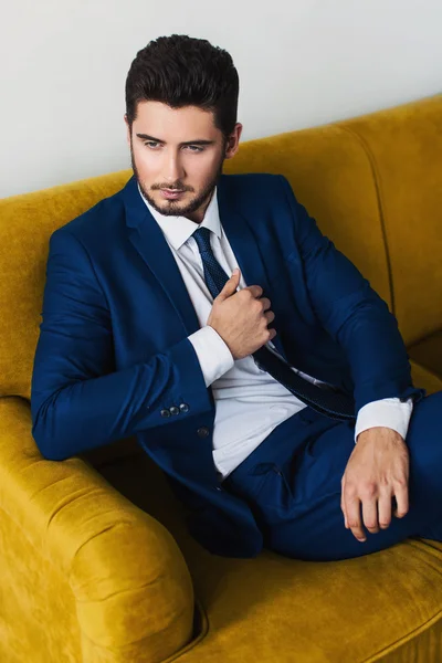 Man posing on sofa in suit