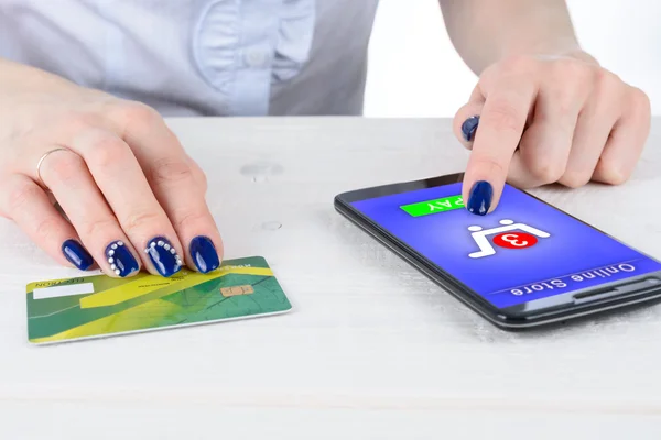 Woman enters credit card details in the smart phone on a white table