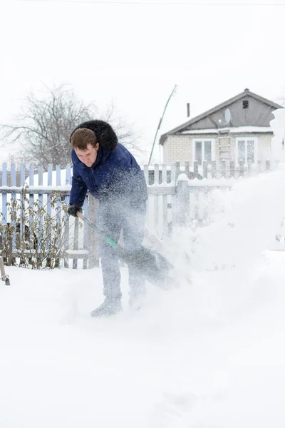 The young man clears snow in the yard