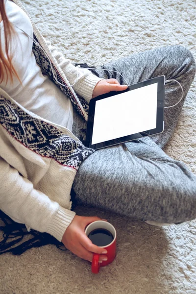 Woman sitting on the couch with tablet and coffee in hand