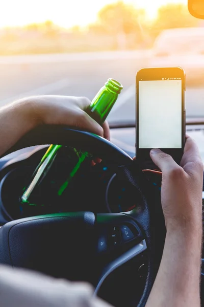 A man driving a car with a bottle of beer and phone