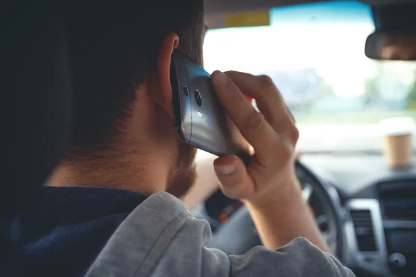 Young man driving a car with phone