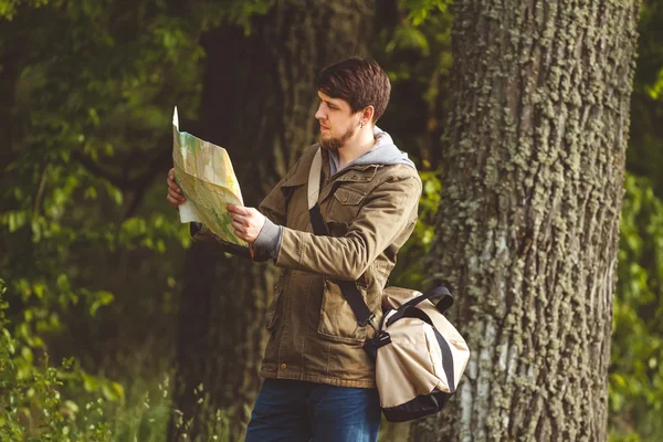 Man with map and bag in hand walking on a roadside