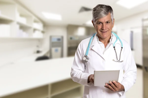 Doctor checking patient notes on a tablet-pc standing with his stethoscope.