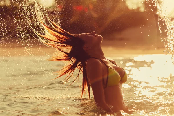 Woman jump hair water splash at sunset