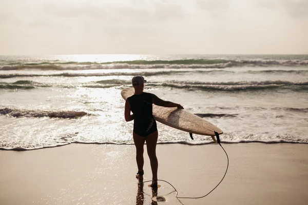 Surfing woman with surfing board back view