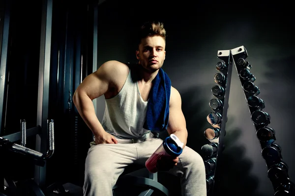 Strong bodybuilder athlete with protein shaker and towel