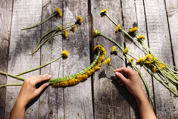 Wreath of dandelions flowers handmade on wood table