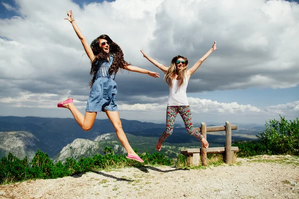 Two girls happy jump in mountains