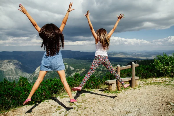 Two girls happy jump in mountains