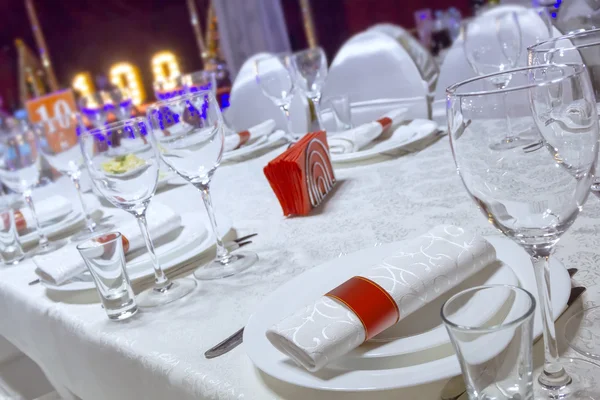A table in the restaurant, the white tablecloth and plates, forks and knifes, glasses, napkins,