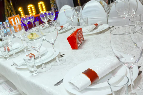 A table in the restaurant, the white tablecloth and plates, forks and knifes, glasses, napkins,
