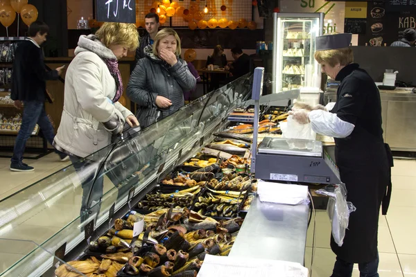 KIEV, UKRAINE - March 12, 2016:seller woman assistant in supermarket selling fresh fish with buyer at shop