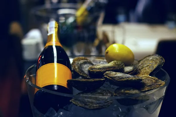 Champagne bottle with lemon and fresh oysters in a bucket with ice