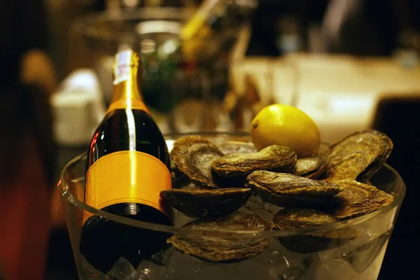 Champagne bottle with lemon and fresh oysters in a bucket with ice