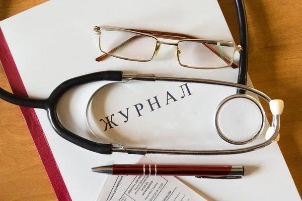 Medical Journal, Pen, stethoscope, glasses and medical certificates on the background of a wooden table. Workplace of a doctor.