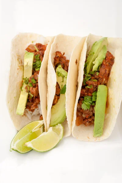 Three homemade soft tacos with ground meat, avocados, cilantro and rice