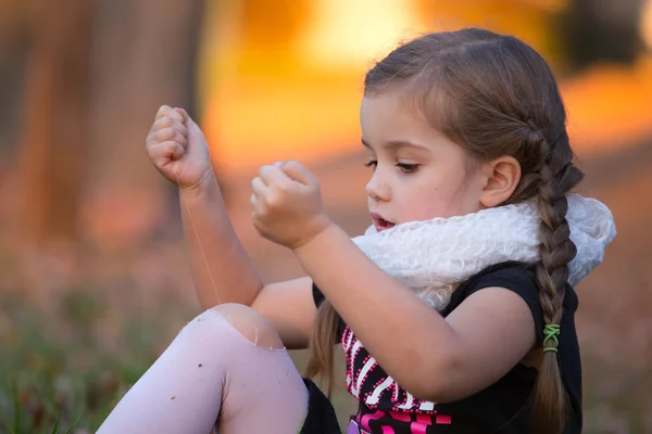 A little girl is trying to fix her hole in her tights