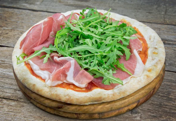 Italian pizza with ham and fresh rocket salad