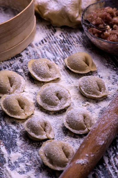 Raw meat dumplings. Ingredients for making dumplings: dough, minced meat, eggs on the wooden background